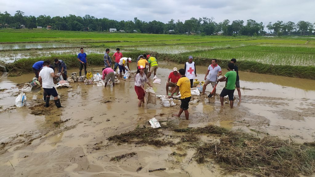 Nepal Red Cross Society volunteers and local people strengthen a breached embankment to prevent floodwater from entering their settlement. Photo by Nepal Red Cross Society