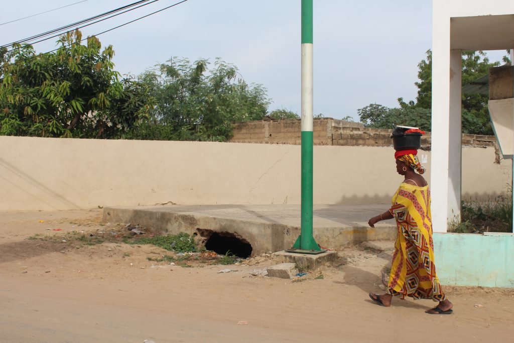 Woman passing a drainage canal in a flood prone part of Thies-Nord.